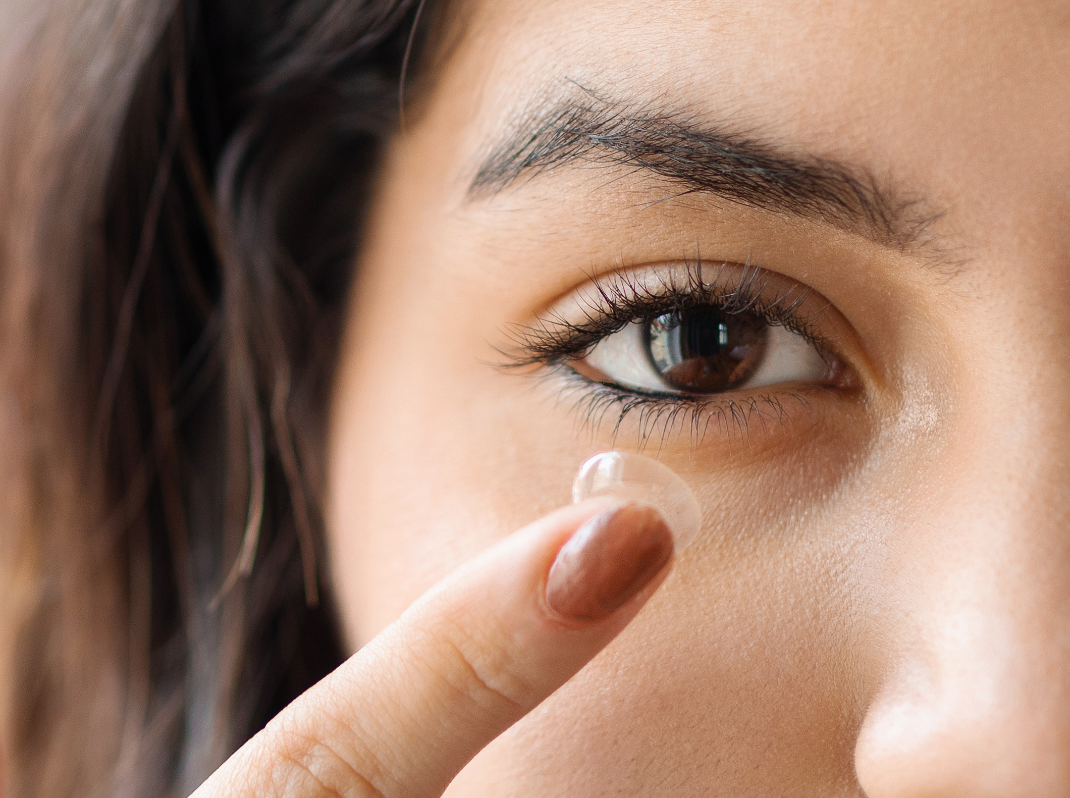 Main banner of woman putting on contact lens.